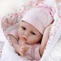 Bambola neonata realistica con occhi azzurri e coperta floreale rosa in luce soffusa - Rosa