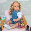60 cm blonde Reborn-Kleinkindpuppe in Jeans-Latzhose auf einem rosa Sofa sitzend - Wie abgebildet / 60 cm