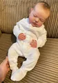 Close-up of 20 inch realistic sleeping reborn baby doll in white long sleeve onesie - Cloth Body With Color Box
