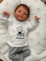 Detail of reborn baby doll wearing white embroidered top with bear and rabbit pattern - Reborn Doll / 49cm