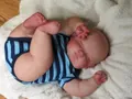 Dettaglio di una bambola reborn neonata realistica che dorme su un tappeto bianco - Grande / Corpo in Tessuto