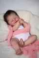 Close-up of sleeping 19-inch reborn baby doll in pink knit wrap on soft white faux fur - 19-inch
