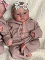 Detailed close-up of a realistic reborn baby doll in a pink knit romper with floral headband - Open eyes / 46cm Cloth Body