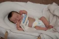 Macro shot of realistic sleeping reborn baby doll with lifelike skin and stripe vest - Girl Style