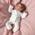 Realistic 10-inch reborn baby doll in white knitted outfit on soft pink fabric - Cloth Body Style / 25cm