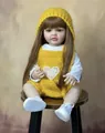 55cm lebensechte Reborn-Puppe Betty mit gelber Strickhose und Mütze, sitzend auf einem Hocker - Gelbes Gestricktes Hosenträger-Set / Gelb