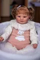 Close-up of Maddie reborn doll with curly hair sitting in a white woven basket - 60cm Height (Maddie Style) / Pink White
