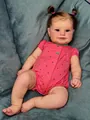 Detailed macro shot of Maddie reborn baby doll with pink hair buns and printed romper - Standard Size / Cloth Body Style