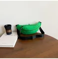 Detail of bright green crossbody sports bag with black strap on a wooden desk - Green