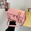 Pink pleated dumpling bag featuring a woven shoulder strap and gold buckle accent - Pink