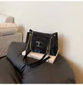 Detailaufnahme der glänzenden schwarzen Faltenledertasche mit goldener T-Metall-Schnalle - Schwarz