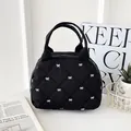 Black quilted makeup bag with white bow pattern and top handle for daily storage - Black