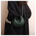 Close-up of deep green woven leather crescent bag with gold buckles and shoulder strap - Green