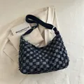 Blaue Tragetasche mit Karomuster, Fransen und breitem Schultergurt auf beigem Blazer - Dunkelblau