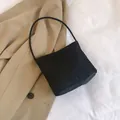 Minimalist black nylon shoulder bucket bag with logo detail on stylish trench background - Black