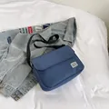 Dark blue canvas messenger bag with adjustable strap and white woven label on top - Blue