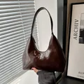 Glänzende dunkelbraune Lackleder-Unterarmtasche in minimalistischer Halbmondform - Braun