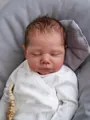 Close-up of lifelike reborn baby doll face featuring realistic skin and soft sheep print outfit - Cloth Body Doll