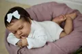 Dettaglio ravvicinato della bambola LouLou Reborn 19 pollici che dorme su un cuscino viola - Corpo in Silicone Integrale / 48cm