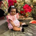 Macro shot of 60cm lifelike dark skin reborn baby doll Maddie in Christmas setting - Cloth Body Style / Deep Skin Pink Outfit