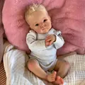 Realistic 18-inch reborn baby doll with blonde curls wearing grey romper on plush cushion - Cloth Body Style / Exquisite Painted Style