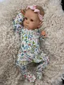 Detailed view of 18 inch realistic reborn doll in floral outfit on plush rug - Bettie Style Cloth Body (YQ015)