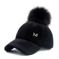 Detail of black faux fur baseball cap with fluffy pom-pom and silver metal M logo - Adjustable / Black (6-Panel Black Pom-pom Snap Style) / Kids