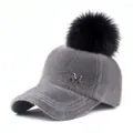 Close-up of grey faux fur winter baseball cap with silver M logo and black pom-pom - Adjustable / Gray (5-Panel Black Pom-pom Pin Style) / Adult