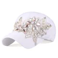 Dettaglio di ricamo floreale dorato con gemme rosa su un cappello bianco da baseball - Bianco