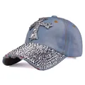 Dettaglio macro della croce con strass e bordi consumati sul cappello in denim - Regolabile / Denim Blu Medio