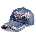 Detailed macro of a navy denim baseball cap featuring large crystal bow and studs - Adjustable / Blue Denim