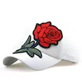 Dettaglio di un berretto bianco con ricamo a forma di rosa rossa e foglie verdi vivaci - Regolabile / Bianco