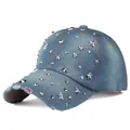 Detail of distressed denim baseball cap featuring silver star studs and pink lining - Denim Navy Blue