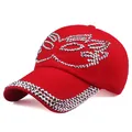 Detail of red baseball cap featuring silver rhinestones in a mask pattern on the front - Red