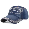 Detailed view of blue denim baseball cap featuring heavy silver rivets and distressed brim - Dark Blue Denim