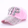 Close-up of pink baseball cap featuring sparkling VIP rhinestone letters and studded brim - Clear Rhinestone Pink
