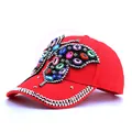 Detailed view of red baseball cap featuring large colorful rhinestone butterfly and studs - Red