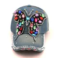Détail macro du papillon en strass sur une casquette de baseball en jean bleu - Denim Bleu Délavé