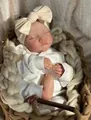 Detailed view of sleeping 19-inch reborn baby doll Levi in white outfit and bow - Cloth Body / Pinkish (As Shown)