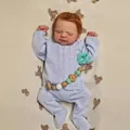 Nahaufnahme der lebensechten Reborn-Puppe mit braunem Haar im blauen Strickoutfit - Stoffkörper-Stil / Lebensechte Neugeborenengröße