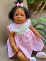 Close-up of 60cm African American reborn baby doll in pink plaid dress with floral details - Simulation Baby Girl Doll / Dark Skin Tone with Pink Plaid Dress / 60 cm