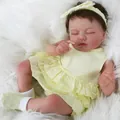 Detailed close-up of 19-inch reborn baby doll sleeping in yellow ruffle dress on white fur - Full Silicone Style / Yellow