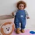 Lifelike 26-inch reborn baby doll wearing denim overalls and boots on a colorful play mat - 66cm Cloth Body (3075)