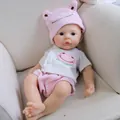 Realistische 12-Zoll-Babypuppe im rosa Frosch-Outfit auf einem weichen cremefarbenen Sofa - Wie abgebildet / 30 cm