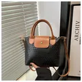 Detalle de textura trenzada de bolso negro en cuero PU con asas marrones y cierre dorado - Negro