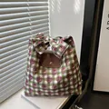 Green checkered tote bag with floral patterns, brown leather flap, and large bow handle - Green