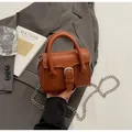 Détail d'un sac vintage marron caramel avec boucle argentée et bandoulière chaîne - Marron