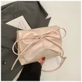 Detailopname van parelroze crossbodytas met grote strik en elegante schouderband - Parelmoer Roze
