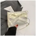 Close-up van de parelwitte geplooide tas met een elegante strik en lederen textuur - Parelwit