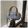 Detail of light blue denim bowling bag with brown leather trim and golden logo - Blue